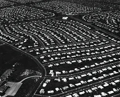 An aerial photograph of Levittown, Pennsylvania shows acres of land with standardized homes in neat rows.