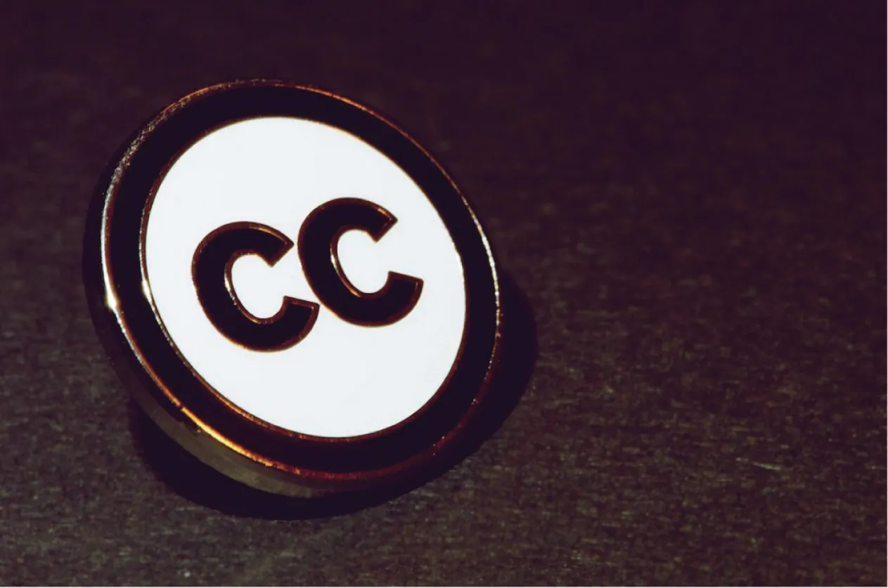 An image of a Creative Commons pin, with the large letters C C.