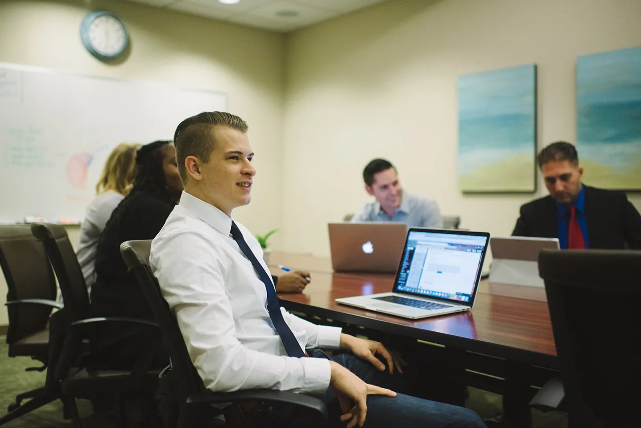A photo shows a group of people attentively listening to a presentation in a meeting.