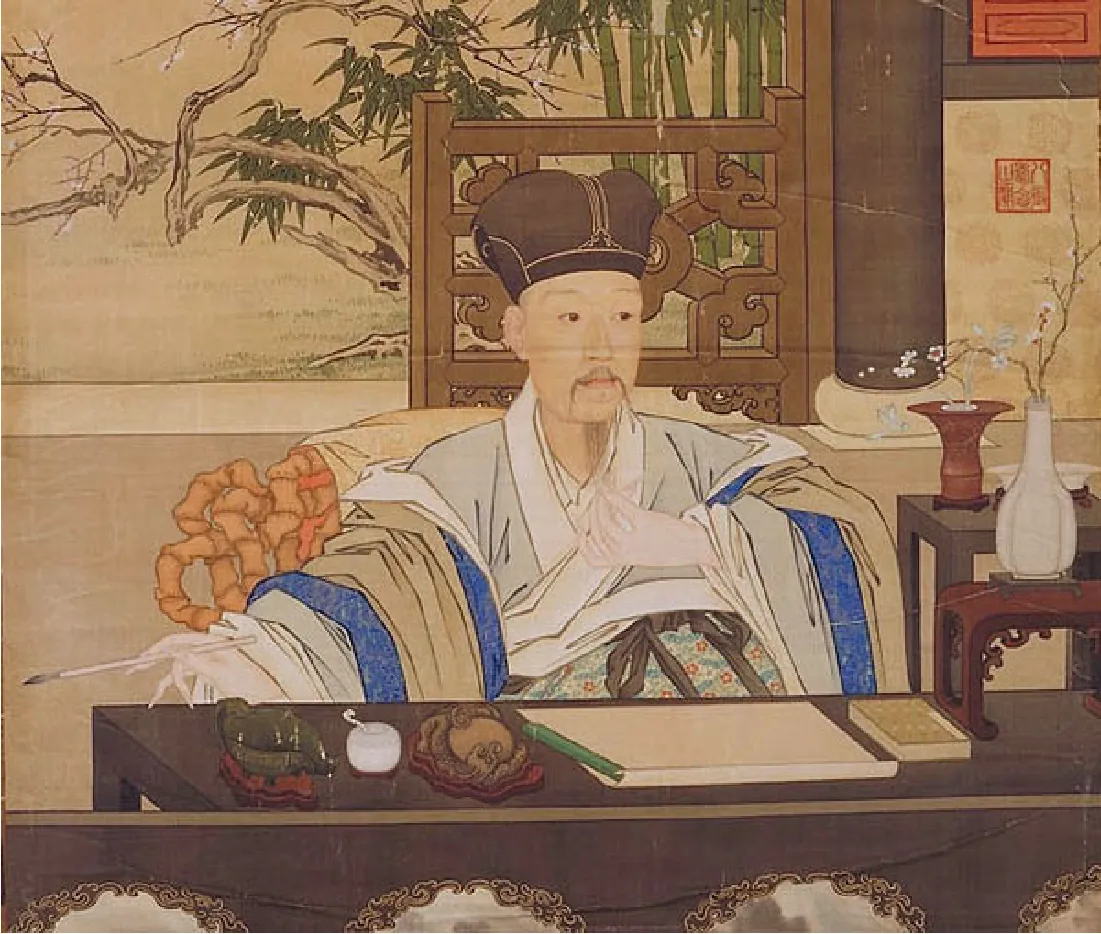 This painting shows Emperor Qianlong. The emperor wears long robes and a hat. He sits at a table with paper and ink nearby. He holds a paintbrush in his right hand and strokes his long beard with his left hand.