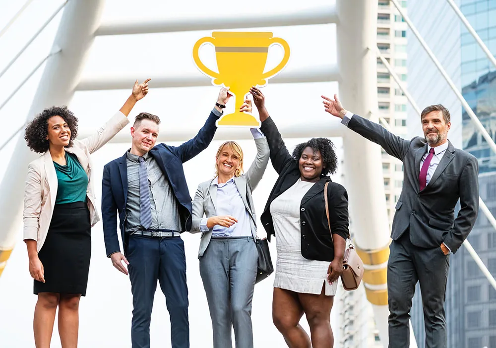 A photo shows a diverse group of employees in an office building holding an award over their heads.