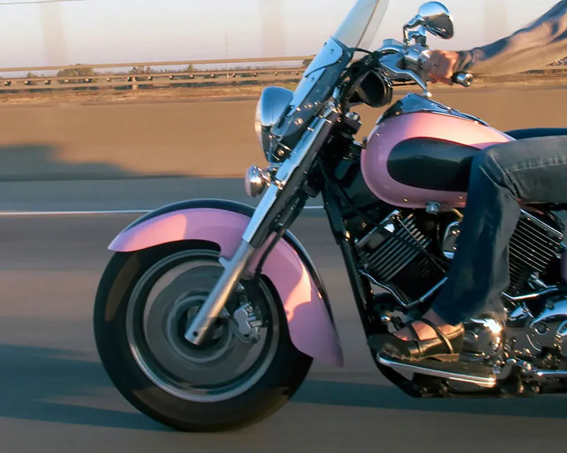 A woman riding a pink motorcycle is shown here.