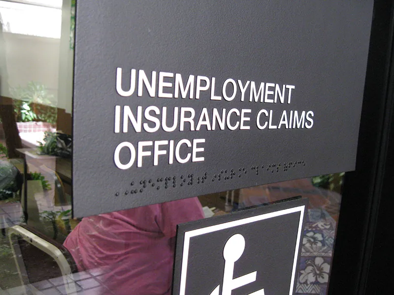 An office signboard reads, “Unemployment Insurance Claims Office.”