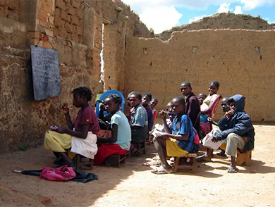 This is an image of children sitting in a ruined structure which serves as their outdoor “classroom.”