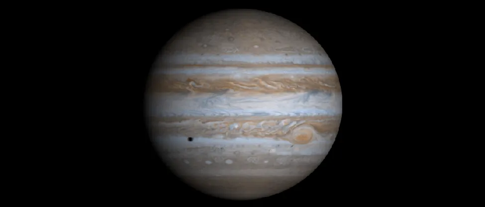 Image of Jupiter taken by the Cassini spacecraft. The alternating light and dark cloud bands are clearly seen, as is the Great Red Spot. At lower left, below the equator, the shadow of one of Jupiter’s moons is projected onto the cloud tops.