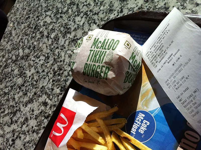 A McAloo Tikki Burger and French fries are on a serving tray next to a receipt.