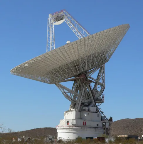 This is a photograph of one of NASA’s Deep Space Network radio telescopes, seen in profile and pointing skyward.