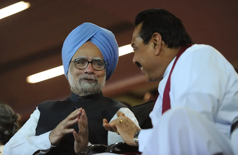 Sri Lankan Prime Minister Manmohan Singh, in a turban and glasses, and Sri Lankan President Mahinda Rajapaksa, smile and talk.