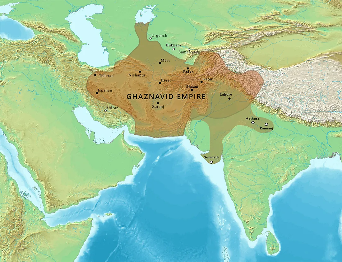 A map is shown. Green areas with some white and brown bumpy regions are shown in an upside down “U” shape with blue in the lower middle. In the middle, a large area is highlighted in gold and labelled “Ghaznavid Empire.” Within this area, these cities are labelled with black dots, from west to east: Teheran, Ispahan, Nishapur, Merv, Herat, Zaranj, Balkh, Ghazni, Kabut, and Lahore. These cities are labelled with a white and black dot: Somnath, Mathura, and Kannauj. The city of Shiraz is labelled outside this highlighted area in the west, and Urgench, Bukhara, and Samarcanda are labelled in the north. All three are labelled with a black and white dot.