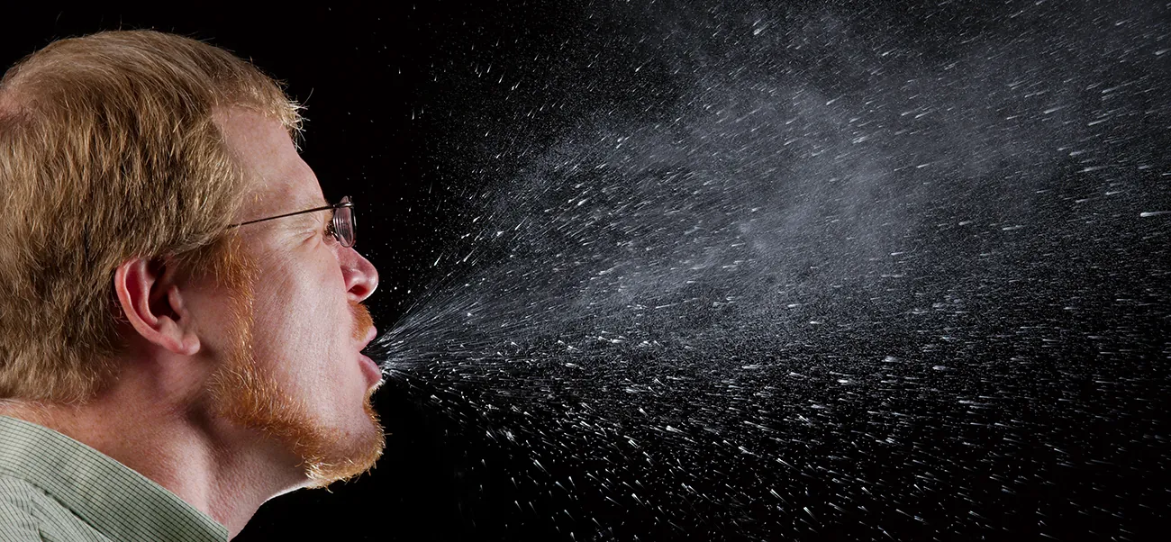 Person sneezing; the sneeze spray is shown.