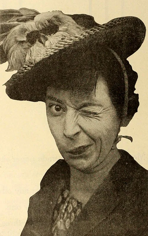 A sepia colored photograph of a woman wearing a large brimmed hat with a feather and winking one eye in an exaggerated manner.