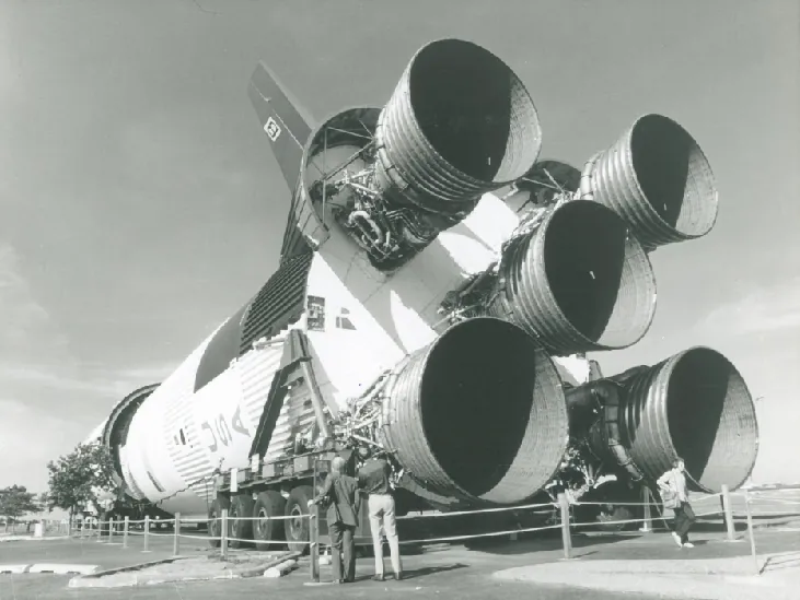 Moon Rocket on Display. Visitors stand in front of the five thrust nozzles of a massive Saturn 5 rocket outside NASA’s Johnson Space Center in Houston.