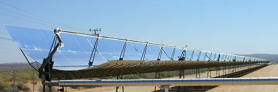 Photograph of several parabolic trough collectors set in a row in an open area.