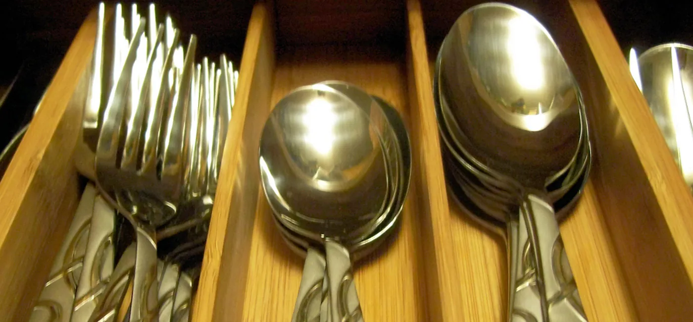 A drawer with three types of silveware in a wooden case.