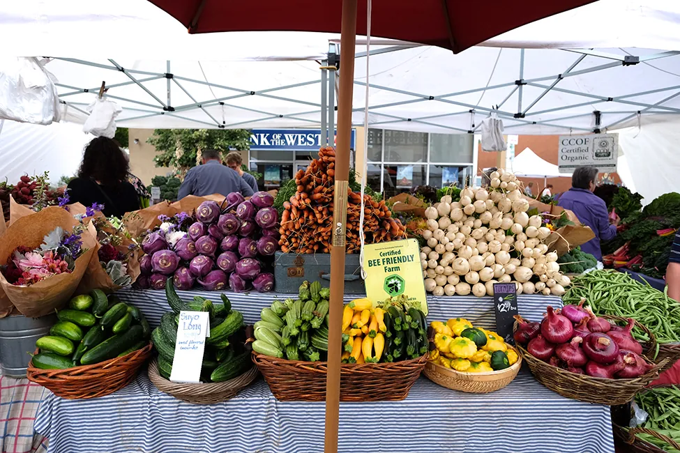 Baskets of vegetables are displayed at a farmers' market.