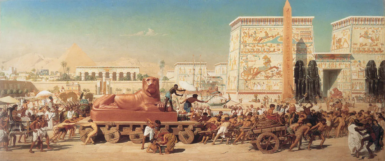 A picture of a painting is shown. In the middle there is a wooden cart with a large golden lion statue on top. Hordes of people are seen struggling to pull and push the cart toward the right on sandy colored ground, wearing various cloths and barefoot. Some are naked. Atop the cart are two dark skinned men, one with a whip in the air while the other holds a white umbrella over the man with the whip. In front of the cart a man is shown on the ground with a man and woman bent over him. Another smaller cart is shown to the right with a large coil of brown rope with a person sitting atop the rope pulled by three men. Behind the statue is a person in long robes sitting in a portable throne being carried by four people in white cloths at their waists. Behind this scene are white and off-white buildings of various shapes and sizes with colorful scenes drawn on the walls. There is a tall brown obelisk in front of one of the buildings on the right with etchings from top to bottom. Next to the obelisk on either side of a large rectangular doorway are two tall black statues of figures wearing elaborate headdresses. In the far left background pyramids can be seen as well as sandy mountains.