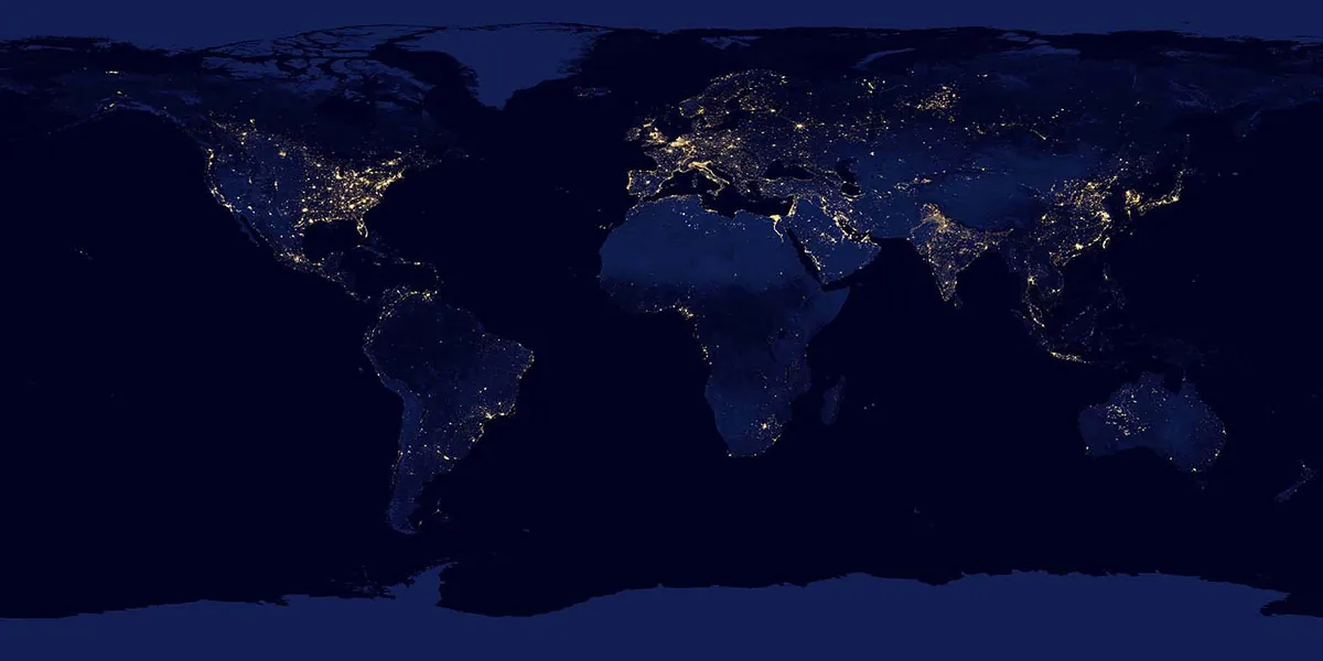 A satellite image of the Earth at night with lights of urban centers noticeable against the background. Areas of light concentration include the eastern half and western coast of the United States and Canada, northern South America, northern Africa, almost all of western Europe, the Middle East especially in the Nile River and Israel areas, most of India, the eastern portions of China and other Southeast Asian nations, and most of Japan.