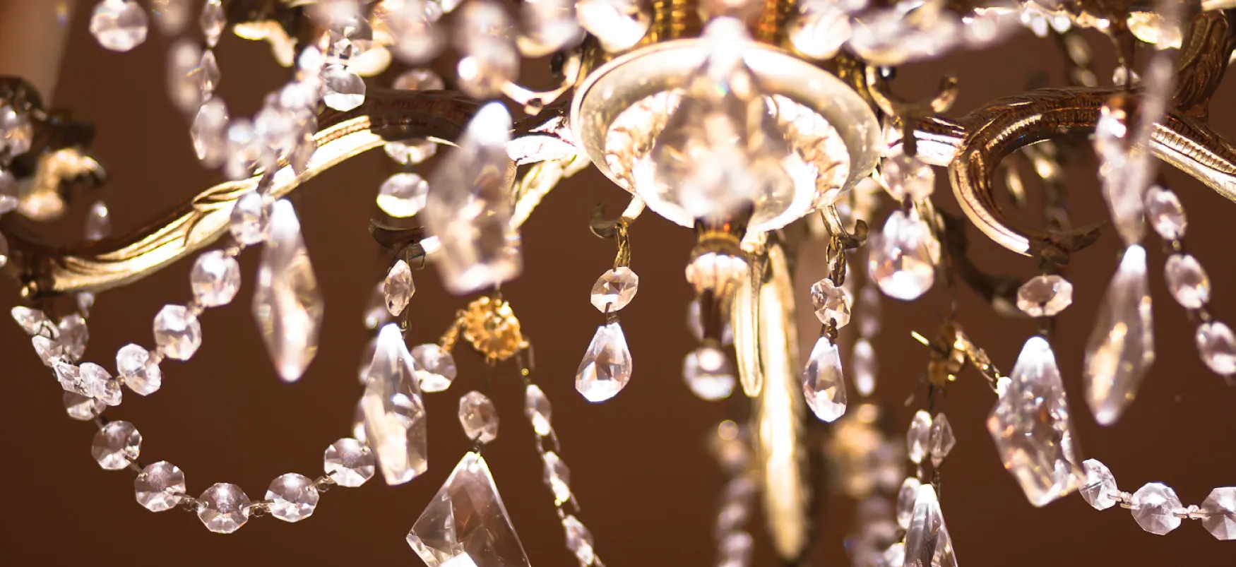 A close-up of teardrop and round Swarovski crystals hanging from a chandelier.