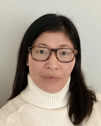 A person wearing glasses and a turtleneck sweater poses for a portrait.