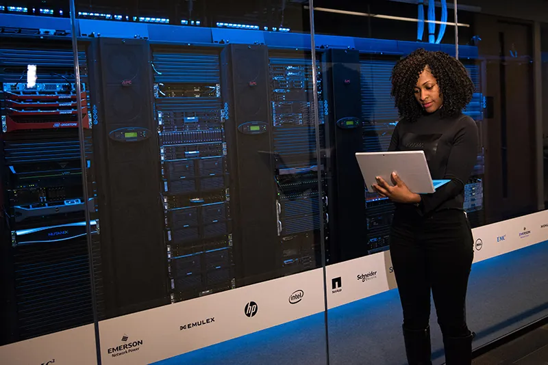 A photo shows a female data center technician working on a laptop in a server room.
