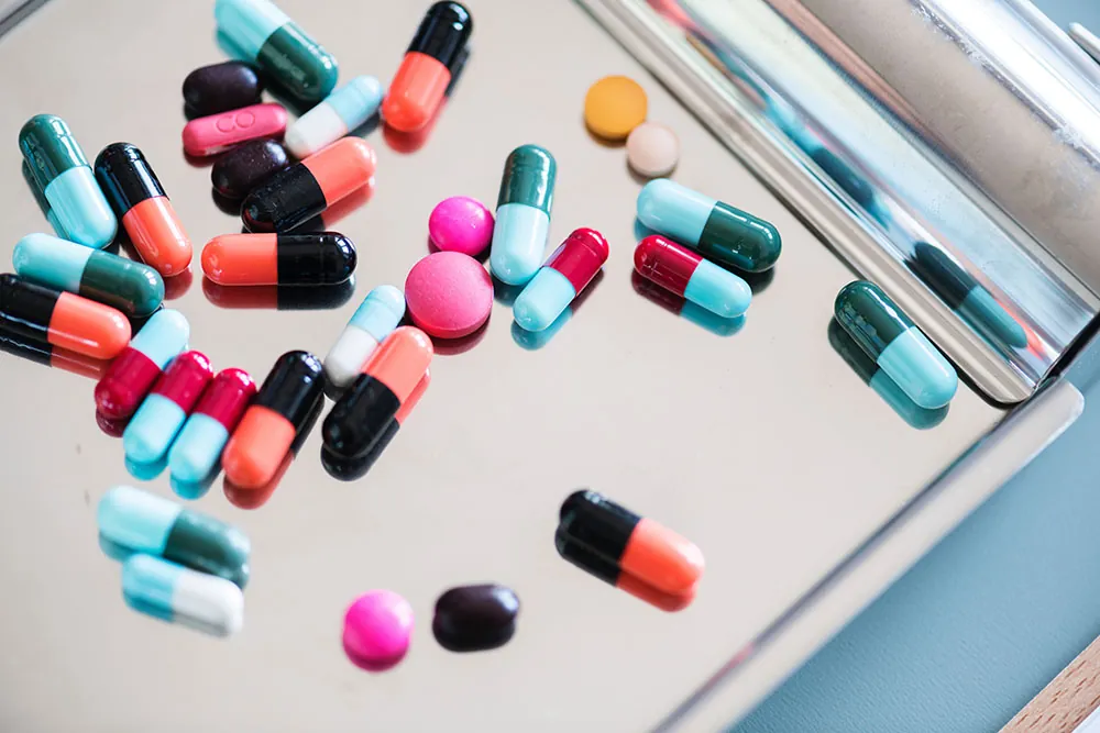 A photo shows assorted pills on a metal tray.