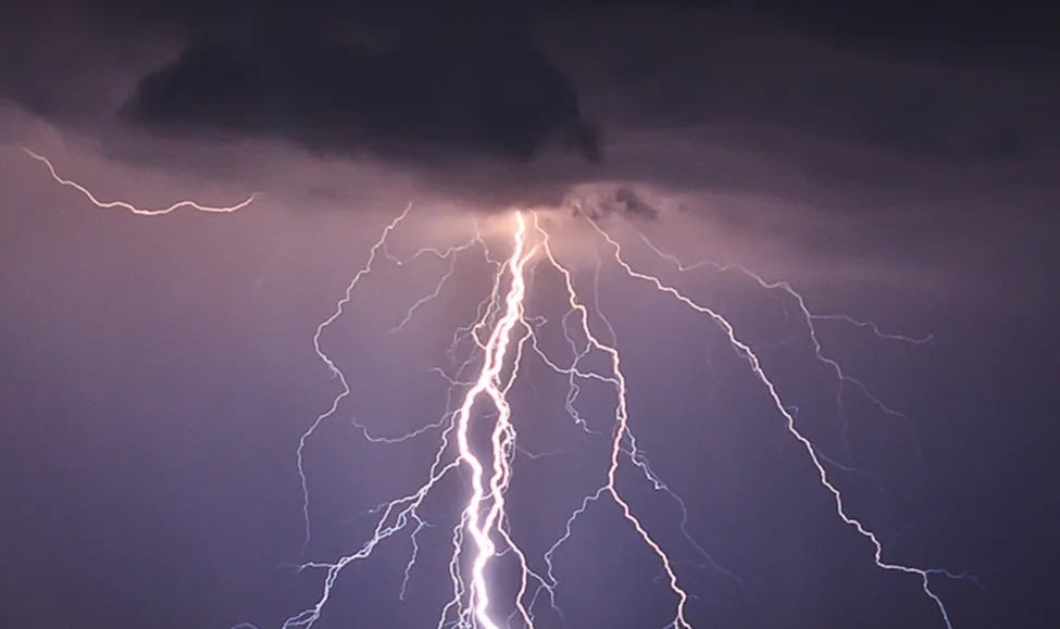 This photo shows branch lightening coming from a dark cloud and hitting the ground.