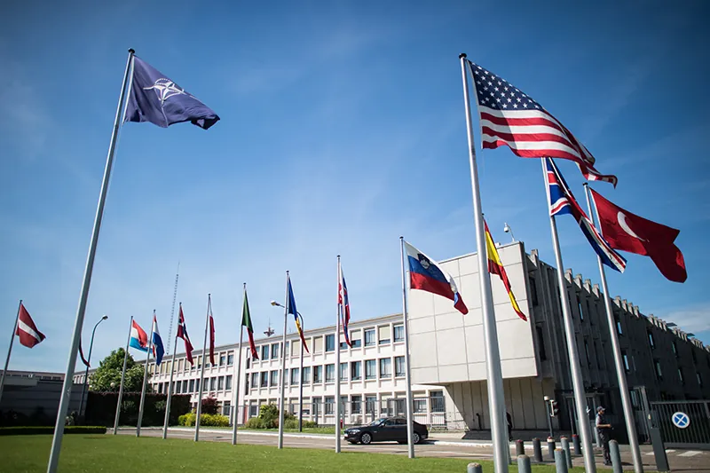 Flags from many different countries fly outside of a large building.