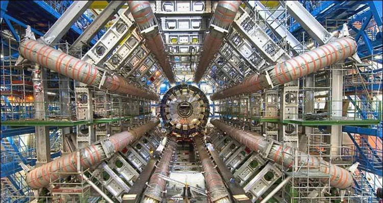 Inside part of the Large Hadron Collider; complex system of machinery and electronics, with a person for scale