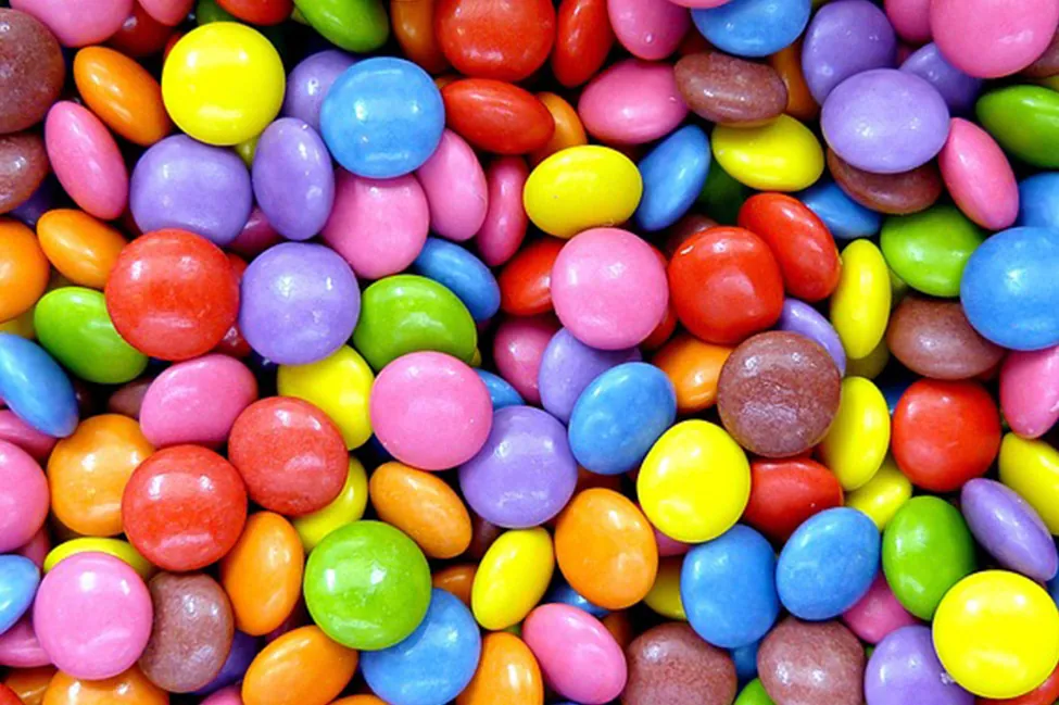 This is a photo of M&Ms piled together. The M&Ms are red, blue, green, yellow, orange and brown.