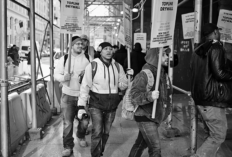Strikers walk a picket line on a city street.
