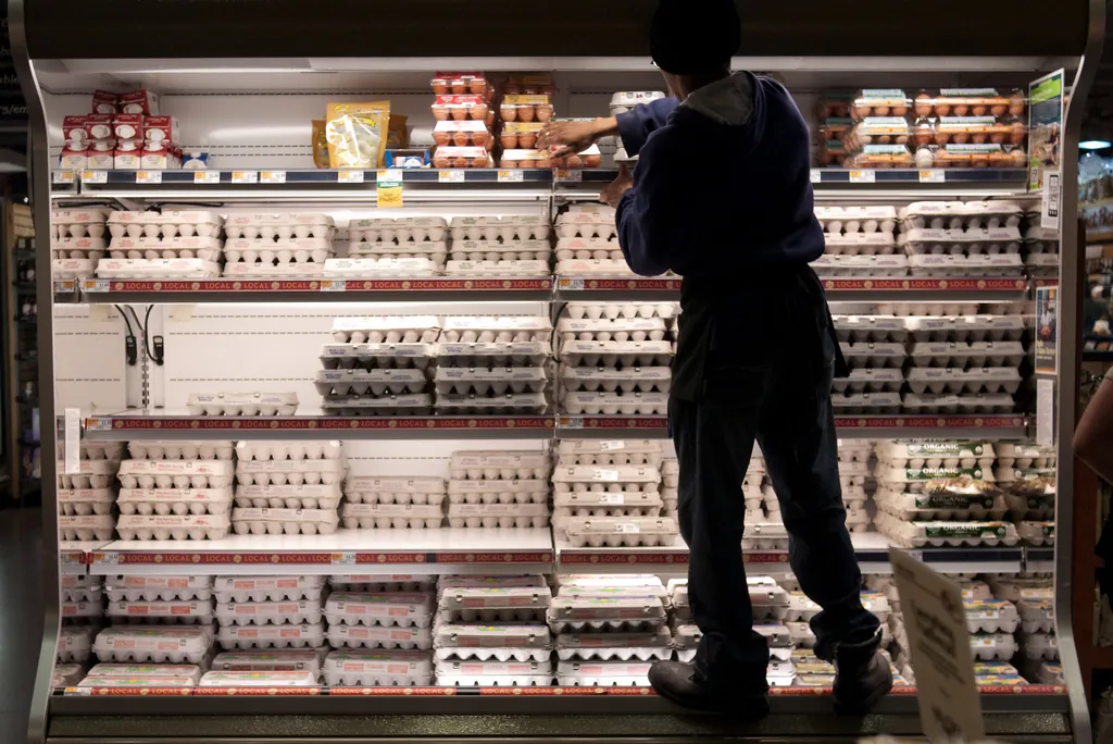A staff stacks eggs on the shelves at a supermarket.
