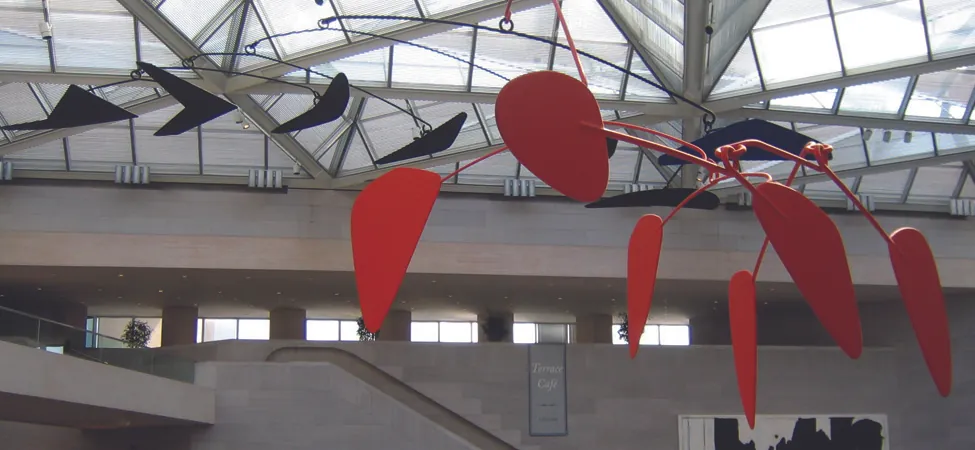 An image of a calder mobile is shown. It has several black and red geometric shapes hanging down.