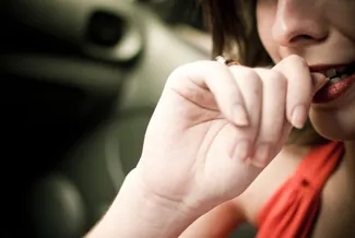 AA photograph shows a woman biting her fingernails. 