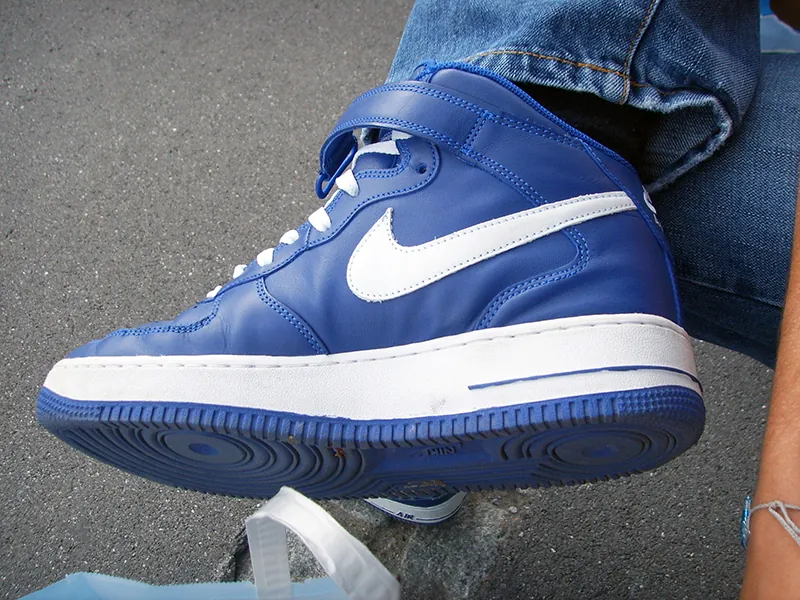 A close up of a foot wearing blue leather Nike high tops.