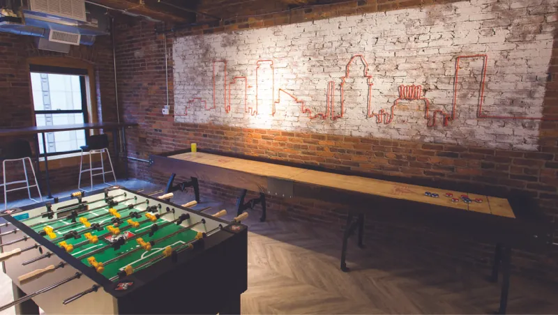 This image shows a room with a shuffleboard table and a foosball table.