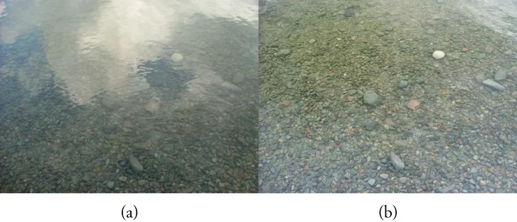This figure shows two photographs arranged side by side. The left photograph, labeled “(a)”, shows a river bed that looks hazy because of interfering gray and white patches. The right photograph, labeled “(b)”, shows the same area of the river bed with almost no interfering gray patches, so that the pebbles on the bed are clearly visible.