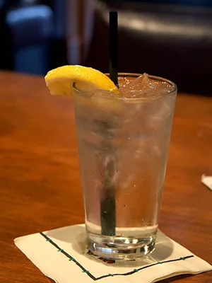 Ice water in a glass with a straw and lemon wedge.