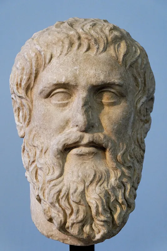 Sculpted bust of a man’s face with thick, shaggy hair and a long curly beard.