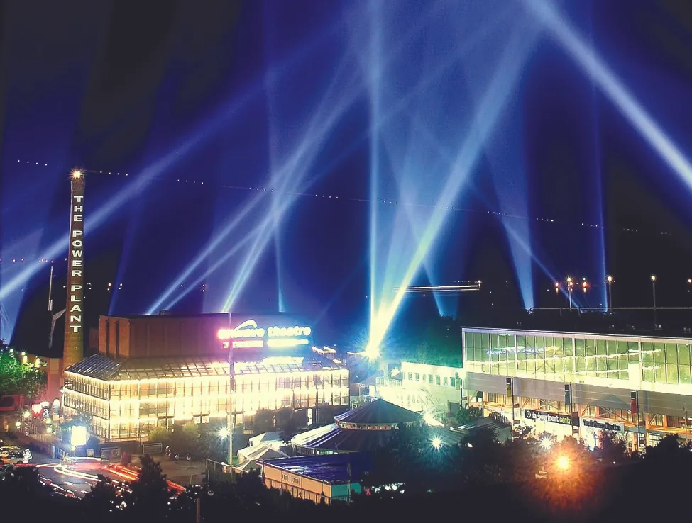 This is a photo of searchlight beams in the night sky of a city scene.