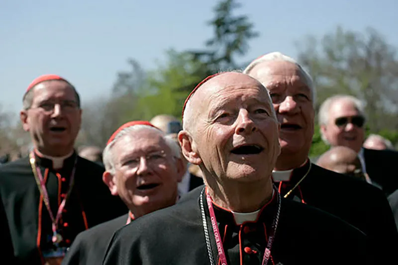 About a half-dozen older men wearing Roman Catholic priestly garb are shown from the shoulders up.