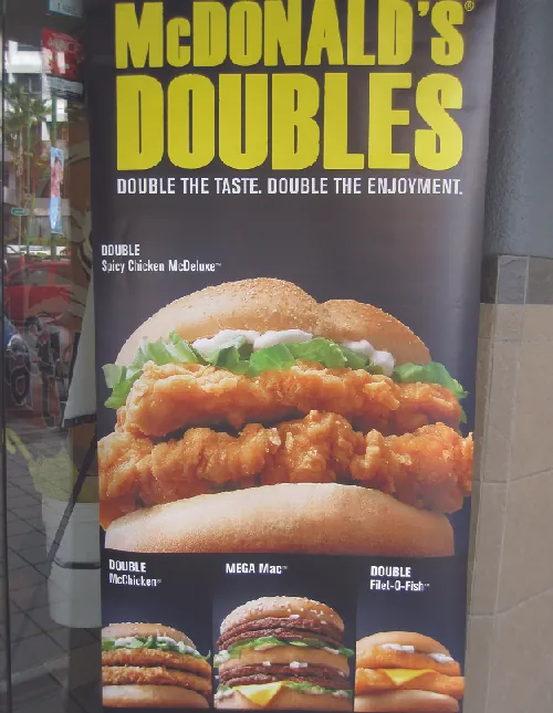 This image shows an advertisement for McDonald’s Doubles. It says “Double the taste. Double the enjoyment.” It shows four sandwiches: the Double Spicy Chicken McDeluxe, the Double McChicken, the Mega Mac, and the Double Filet-O-Fish.