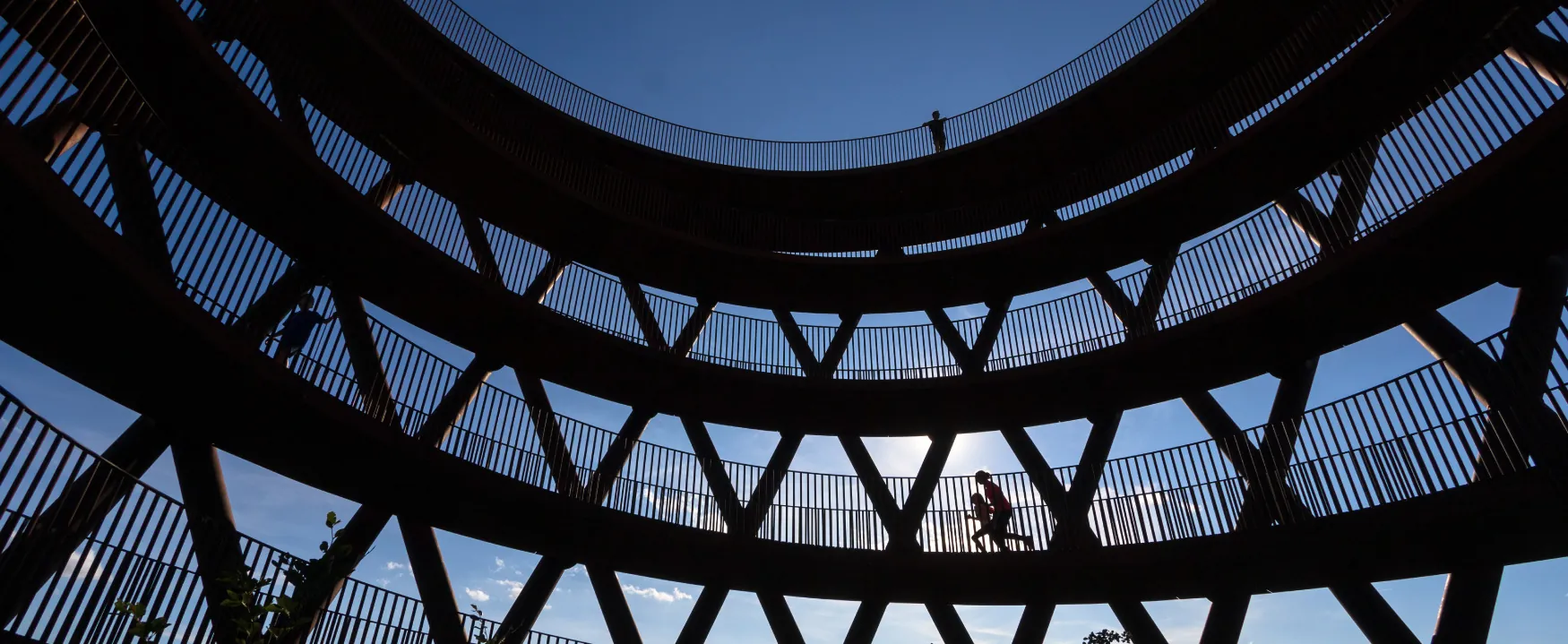 A photo shows a low-angle view of silhouettes of people walking or running in the high observation tower, Camp Adventures in Haslev on the South Island of New Zealand.