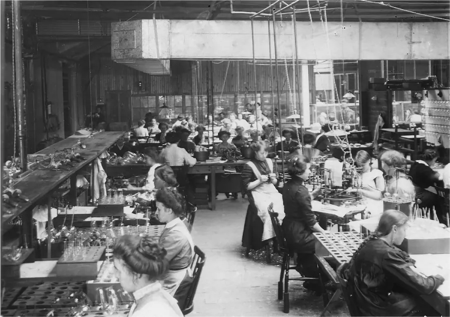 This photograph shows a large factory where women and girls are building lamps.
