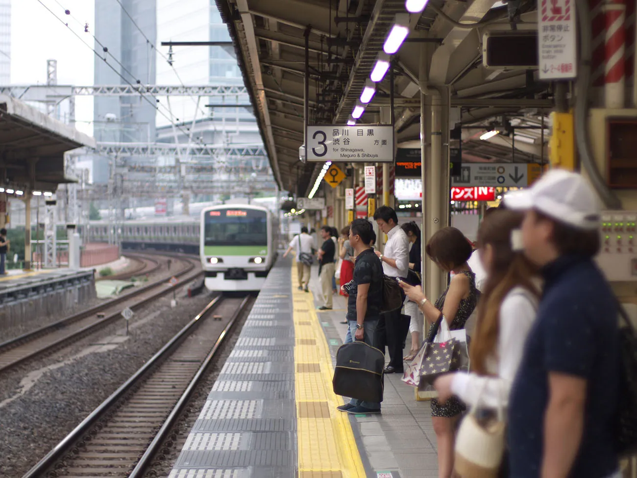 A photo shows passengers waiting while a train enters the platform at a railway station in Japan.