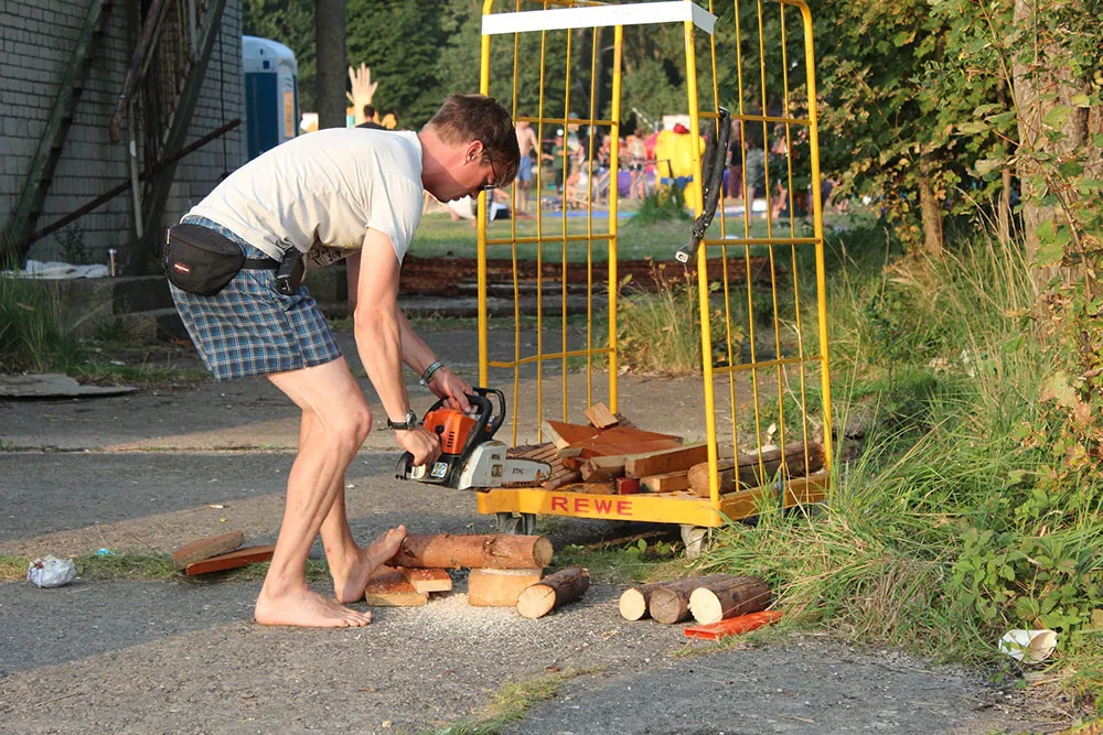 A photo shows a man sawing wood by holding it in place with his bare foot.
