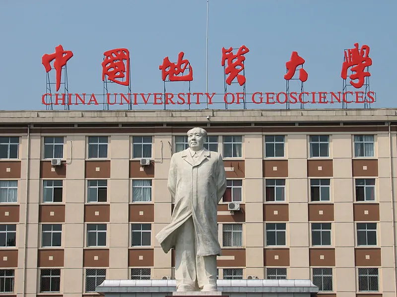 Statue of Chairman Mao in front of a large, modern building with a sign in both Chinese characters and English letters. The English letters read “China University of Geosciences”.