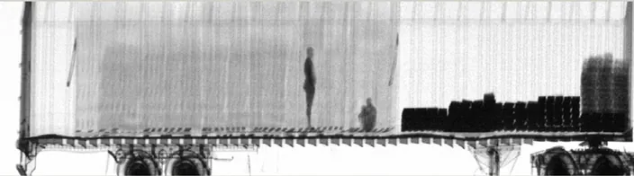 Gamma-ray scanned image of two stowaways hiding inside a big truck.