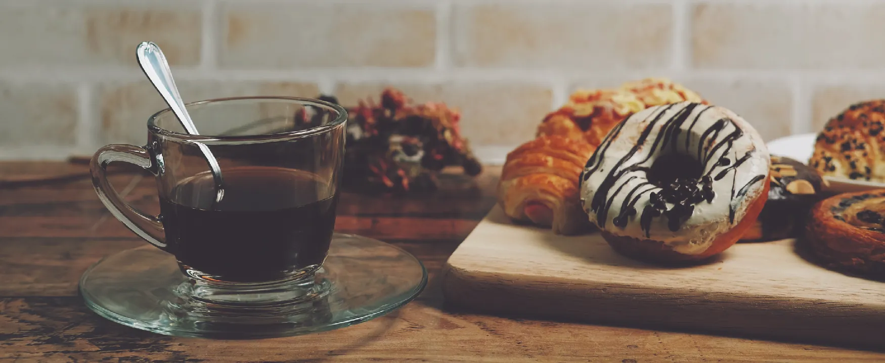 Picture of a cup of coffee beside a board with various pastries.
