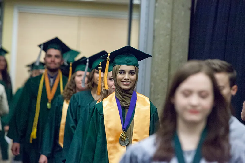 A photo shows a group of graduate students smiling as they walk forward in a line.