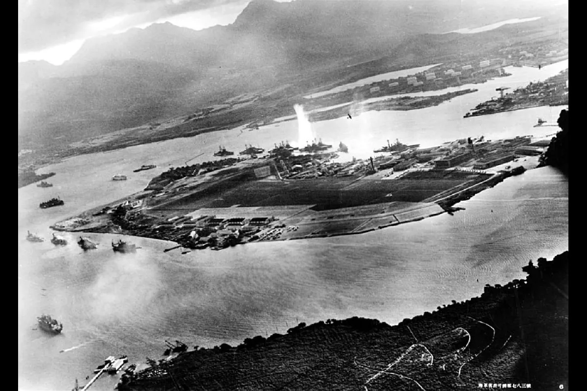 This photograph shows an aerial view of an island with mountains in the background. There is a large splash in the water near the island.